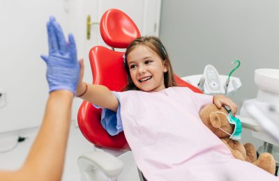 Cute little girl sitting on dental chair and having dental treatment.