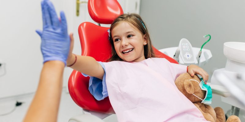 Cute little girl sitting on dental chair and having dental treatment.